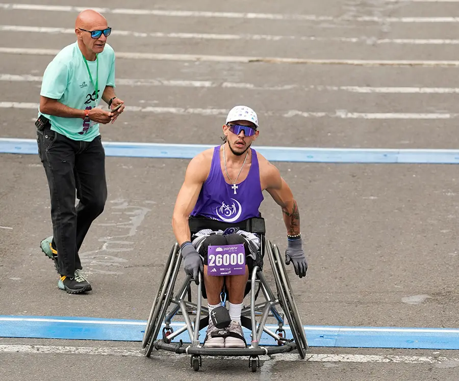 Atleta en silla de ruedas de carreras compitiendo junto a corredores convencionales en evento inclusivo