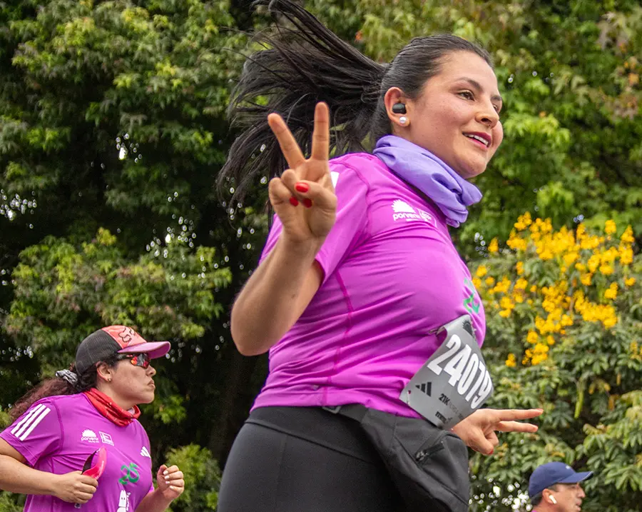Corredora corriendo motivada con audífonos y música durante la media maratón de Bogotá 2025