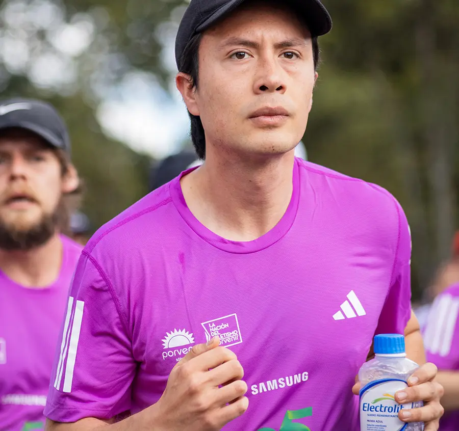 Corredor hidratándose estratégicamente durante estación de agua en carrera de 10K