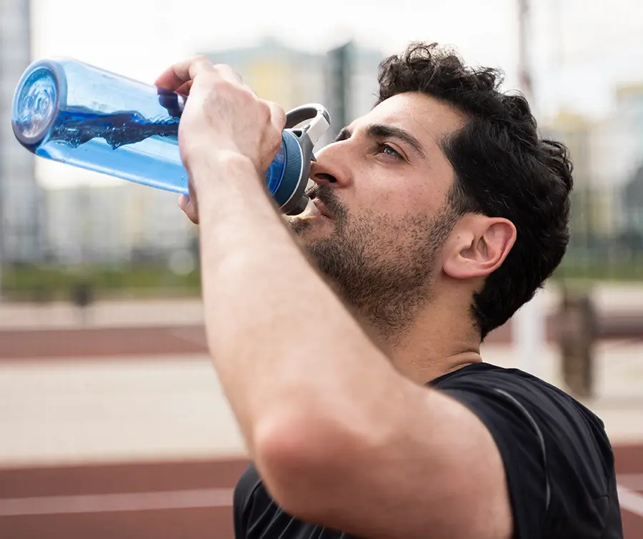 Corredor hidratándose estratégicamente en estación de agua durante media maratón