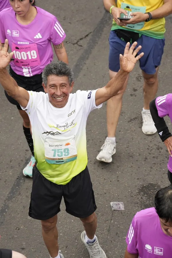 Runner senior cruzando meta de carrera con expresión de logro y satisfacción