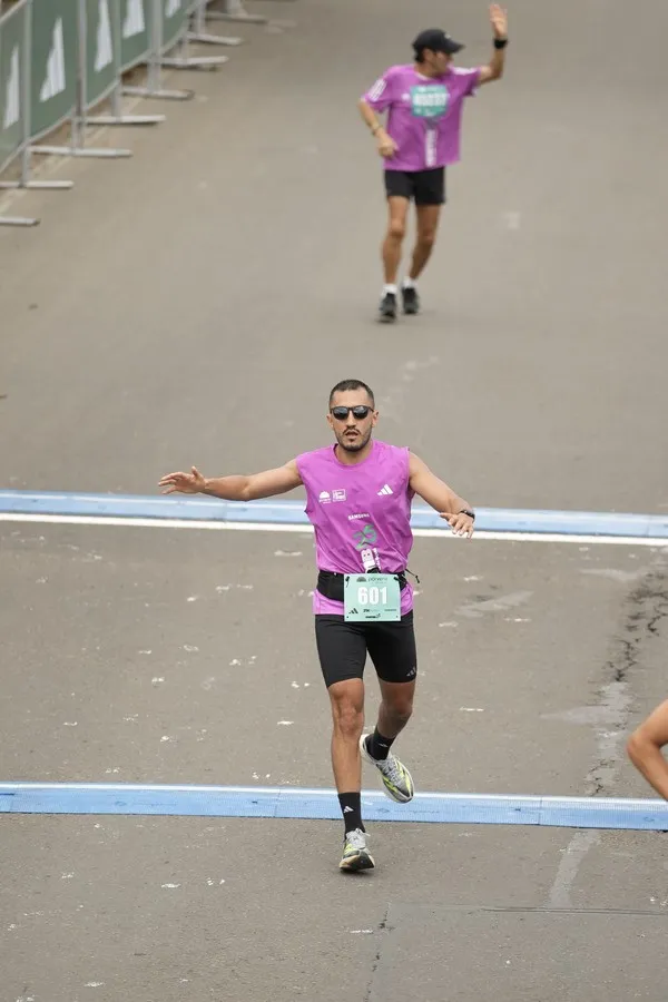 Corredor ejecutando protocolo de recuperación post media maratón con elevación de piernas