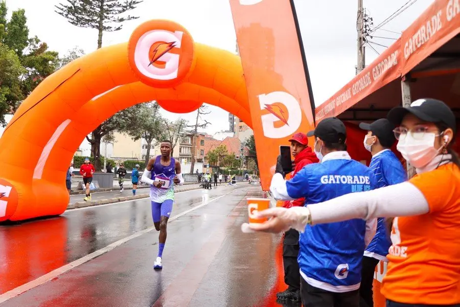 Isla de servicio con hidratación y personal de apoyo para corredores durante la media maratón de Bogotá 2026